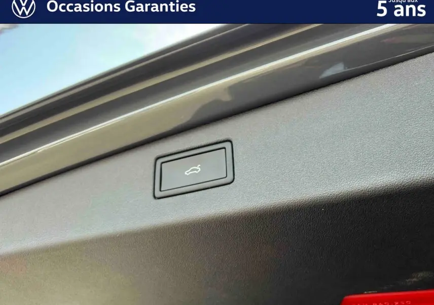 Bouton d'ouverture électrique du coffre sur la partie intérieure du hayon d'un Volkswagen Tiguan gris.