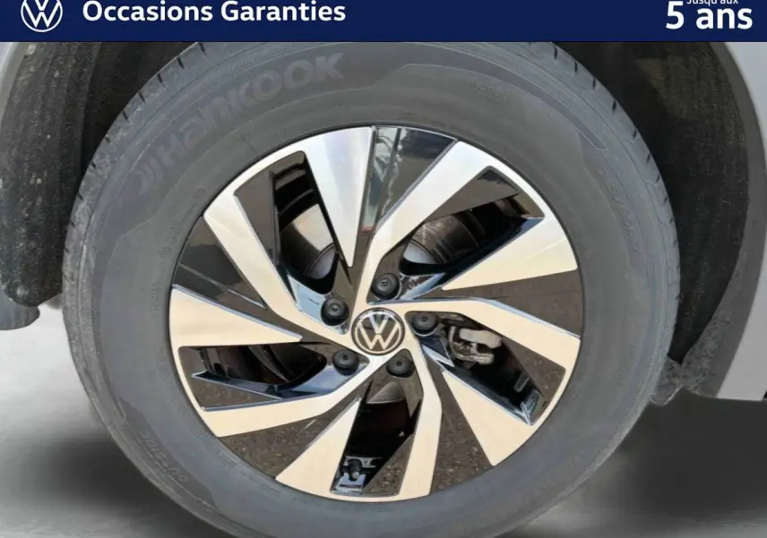 Gros plan sur la jante alliage Venezia noire et brillante du Volkswagen Tiguan gris, mettant en valeur le logo VW central.