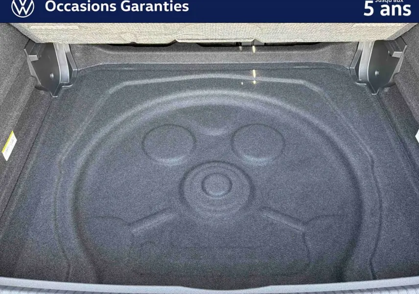 Coffre ouvert d’un Volkswagen Tiguan gris, vue plongeante sur le compartiment de rangement vide.