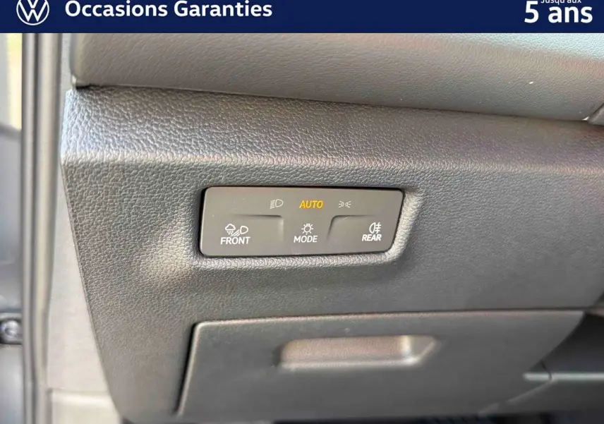 Détail du tableau de bord du Volkswagen Tiguan 2025 montrant les commandes d'éclairage automatiques en plastique noir texturé.