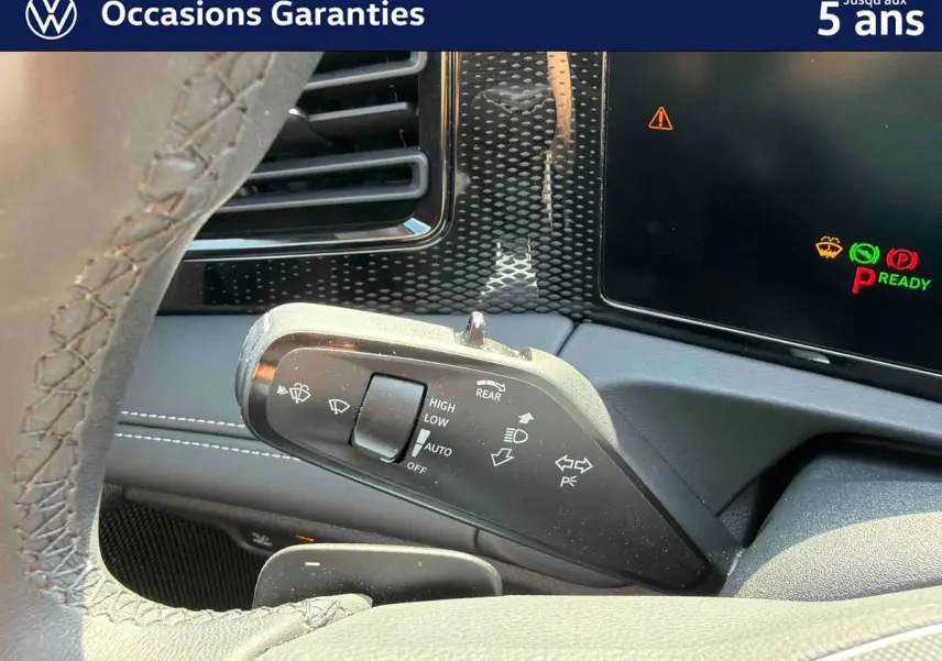 Gros plan sur la commande des essuie-glaces à gauche du volant dans l’habitacle d’un Volkswagen Tiguan gris.