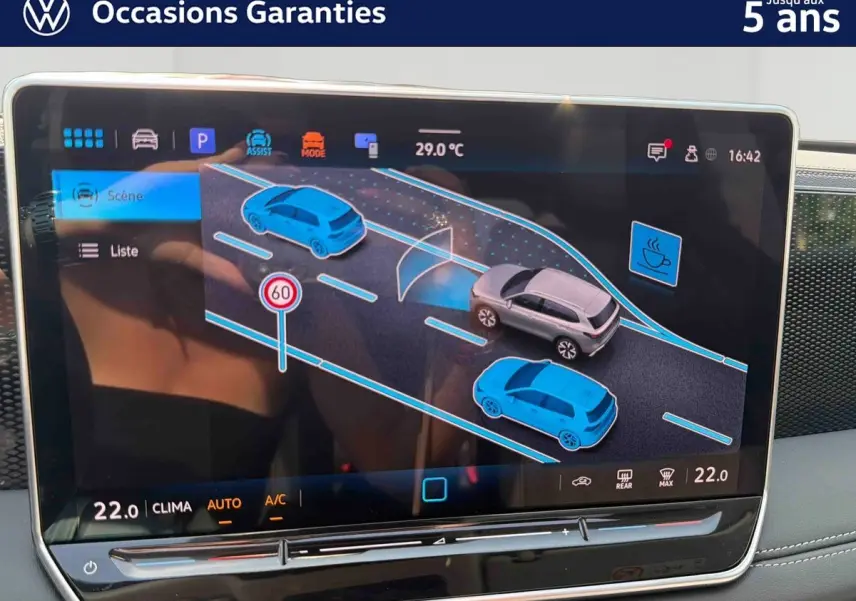 Écran tactile intérieur du Volkswagen Tiguan 2025 montrant l'assistance à la conduite avec véhicule gris en vue de profil.