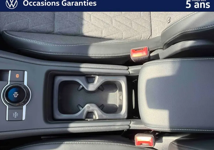 Vue plongeante sur la console centrale noire du Volkswagen Tiguan 2025, avec porte-gobelets et frein de stationnement électronique.