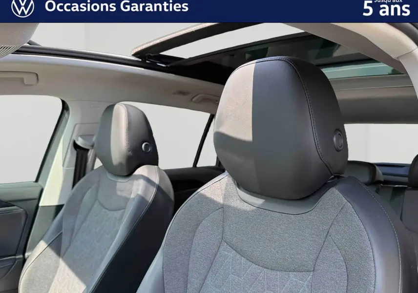 Gros plan sur les sièges avant gris et noirs du Volkswagen Tiguan 2025 avec toit panoramique ouvert.