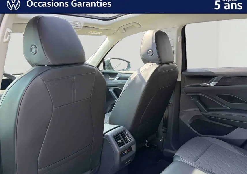Vue arrière intérieure du Volkswagen Tiguan gris 2025, montrant les sièges avant en cuir et la console centrale avec aérateurs.