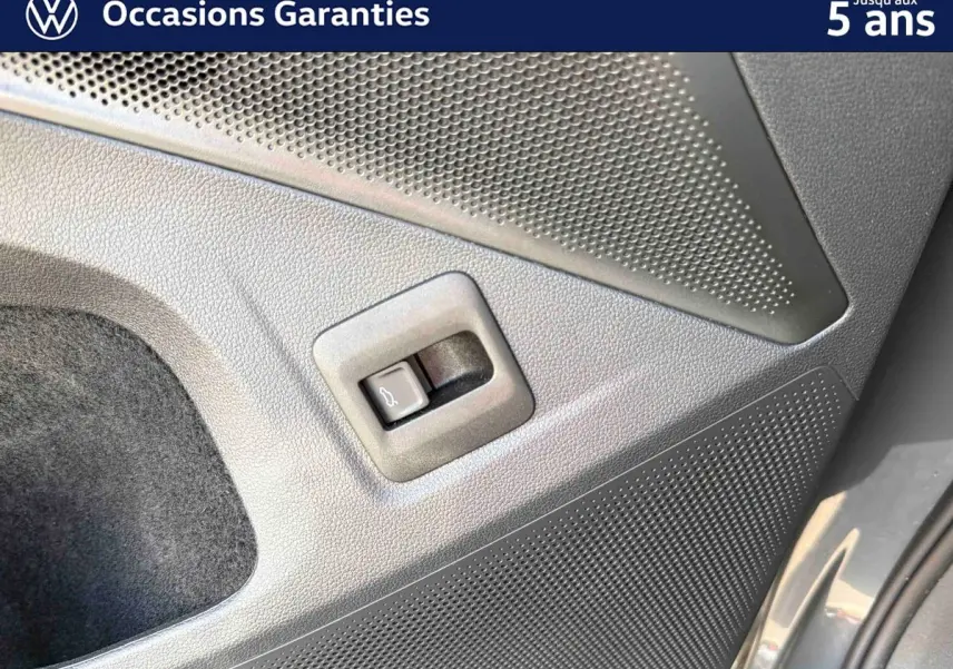 Détail du bouton d'ouverture électrique du coffre sur la porte arrière droite d'un Volkswagen Tiguan gris 2025.