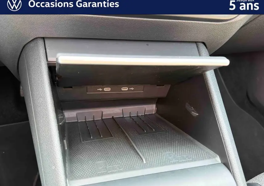 Gros plan sur la console centrale du Volkswagen Tiguan gris, montrant les ports USB-C et le compartiment de rangement ouvert.