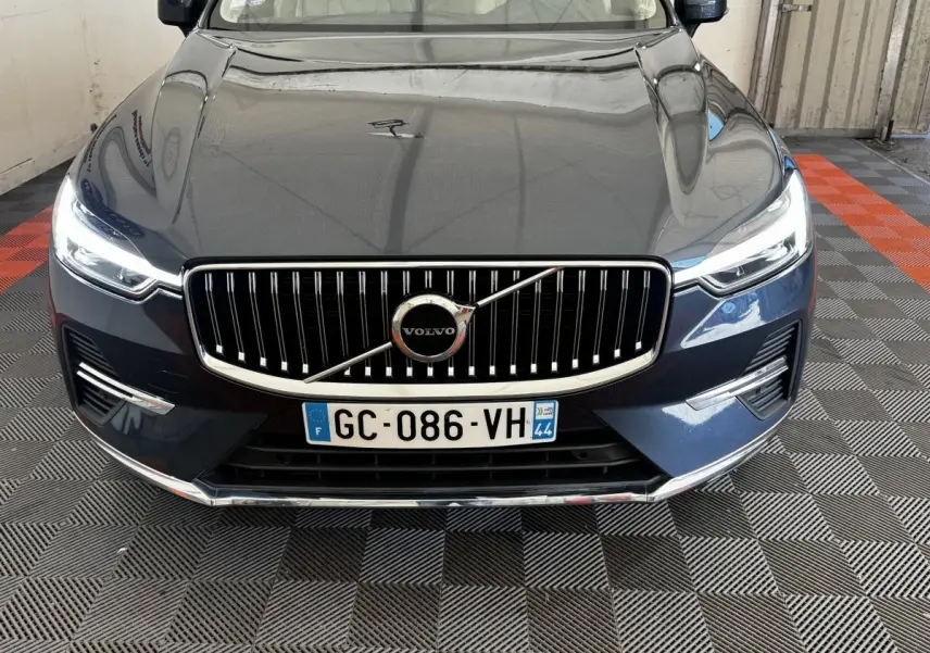 Vue avant rapprochée du Volvo XC60 bleu avec calandre verticale chromée et phares LED allumés.