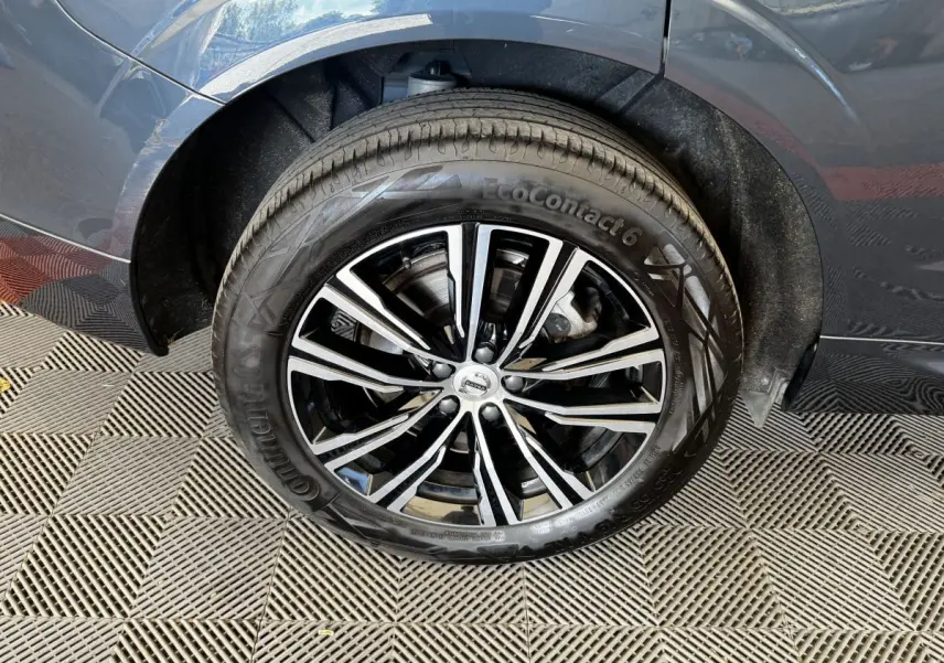 Gros plan sur la roue avant gauche du Volvo XC60 bleu, mettant en valeur la jante alliage noire et argentée.