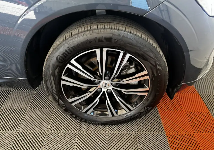 Gros plan sur la roue avant droite du Volvo XC60 bleu, mettant en valeur la jante alliage noire et argentée.