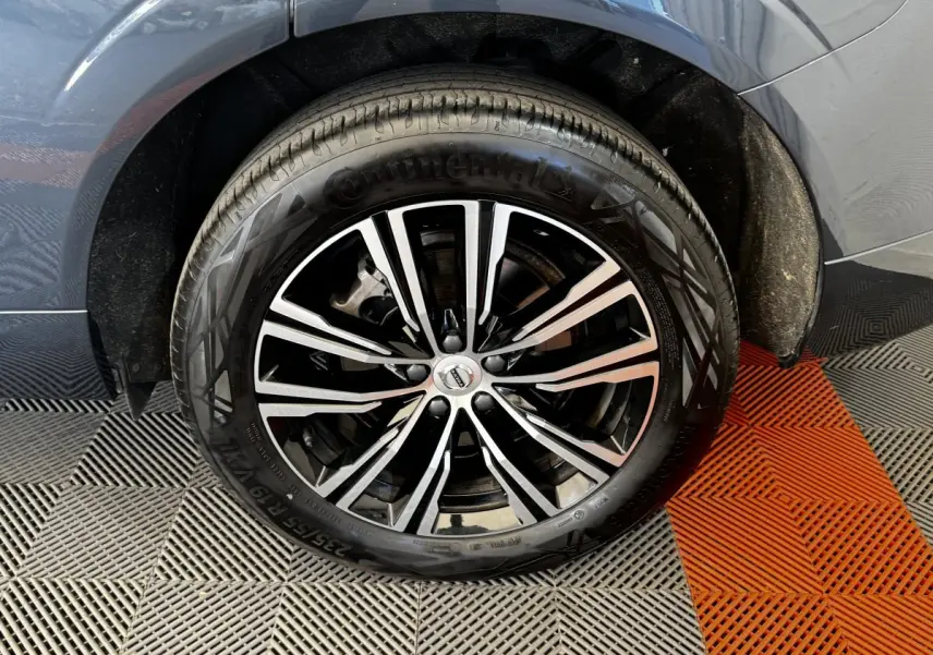 Gros plan sur la roue avant droite avec jante alliage bicolore du Volvo XC60 bleu hybride rechargeable.