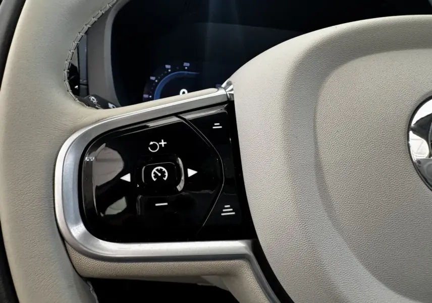 Gros plan sur les commandes de régulateur de vitesse à gauche du volant beige du Volvo XC60 Recharge T8 2021.
