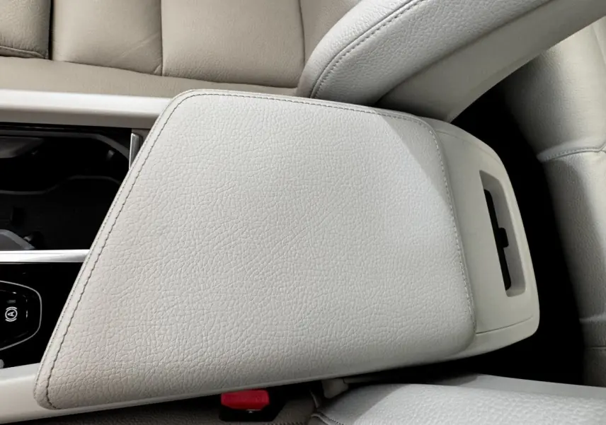 Détail de l'accoudoir central en cuir beige clair du Volvo XC60 Recharge T8 2021, avec console et bouton frein à main visible.
