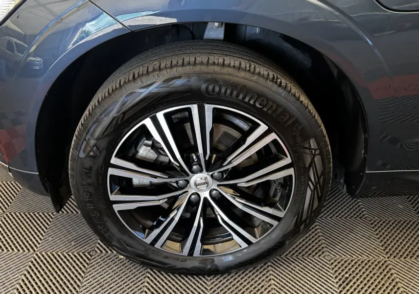Gros plan sur la roue avant droite d’un Volvo XC60 bleu, jante alliage noir et argent avec pneu Continental.