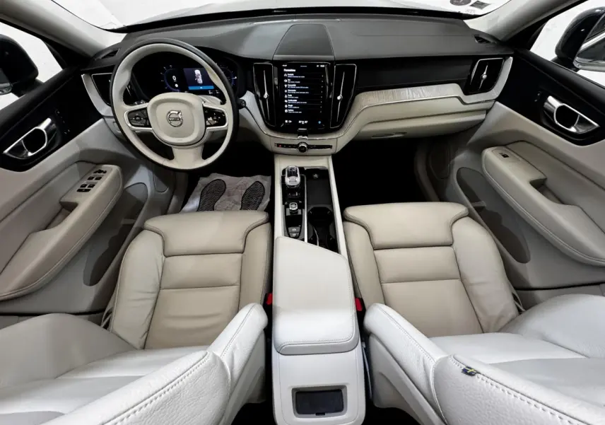 Intérieur clair du Volvo XC60 Recharge T8 2021, vue avant centrée sur tableau de bord et sièges cuir beige.