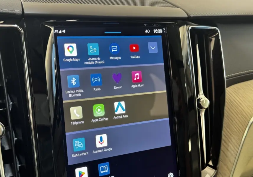 Écran tactile central du tableau de bord du Volvo XC60 bleu, affichant les applications multimédia et navigation.