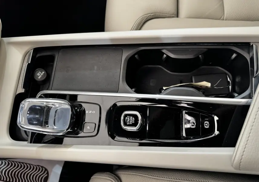Vue rapprochée de la console centrale beige du Volvo XC60 bleu, avec levier de vitesses cristal et bouton start/stop.