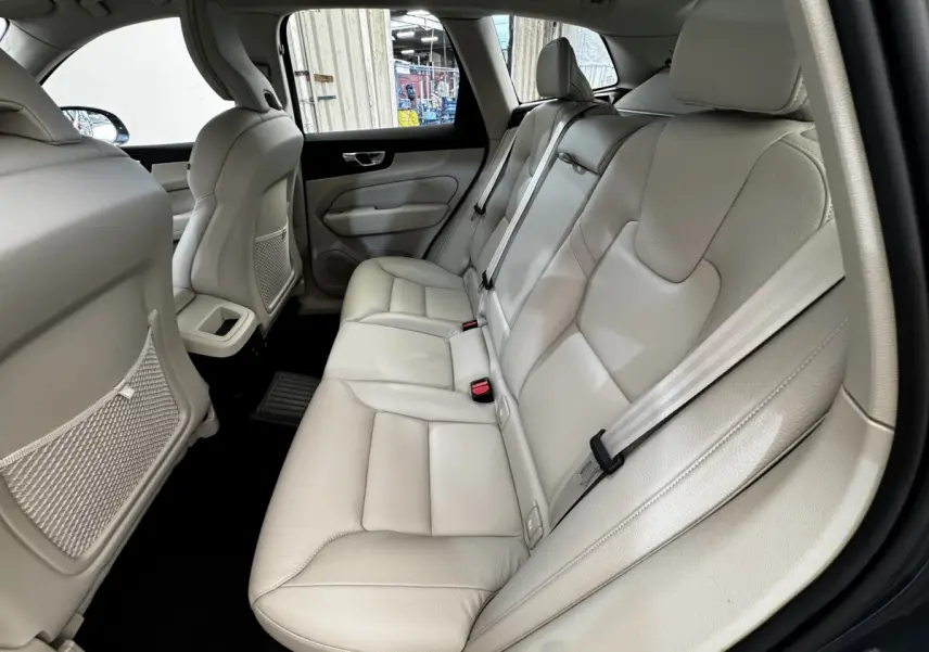 Vue intérieure côté droit des sièges arrière en cuir beige clair du Volvo XC60 bleu, avec ceintures de sécurité visibles.