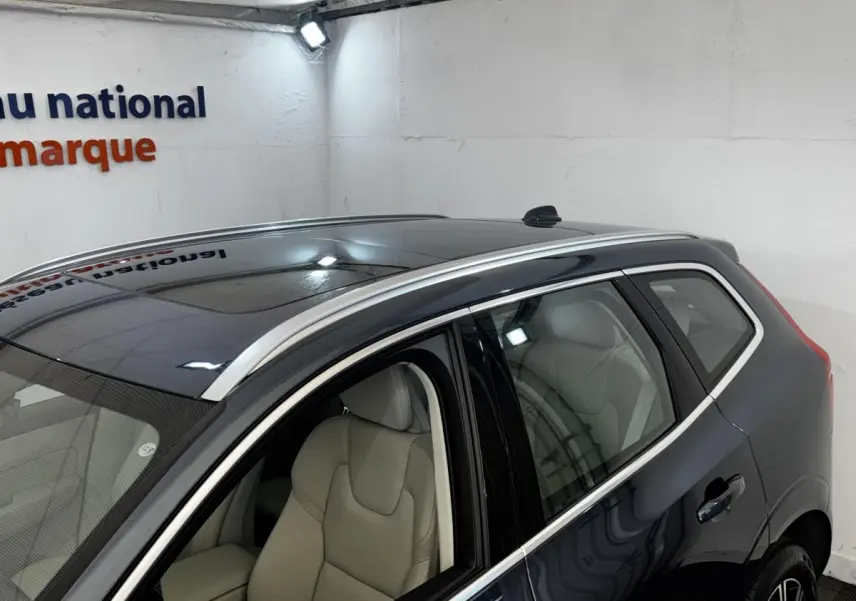 Vue 3/4 arrière droite d’un Volvo XC60 bleu avec toit ouvrant et sellerie claire visible à l’intérieur.