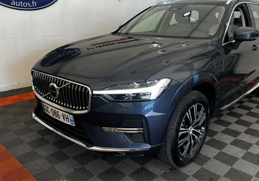 Vue 3/4 avant droit d’un Volvo XC60 bleu avec calandre chromée et jantes alliage noires.