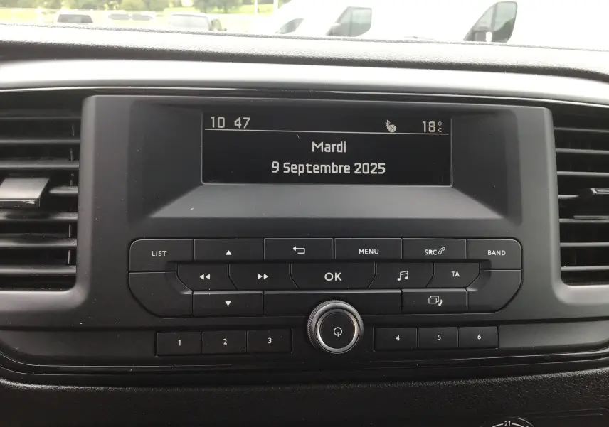 Affichage central de la console multimédia de l'Opel Vivaro blanc, avec écran digital et commandes tactiles visibles.