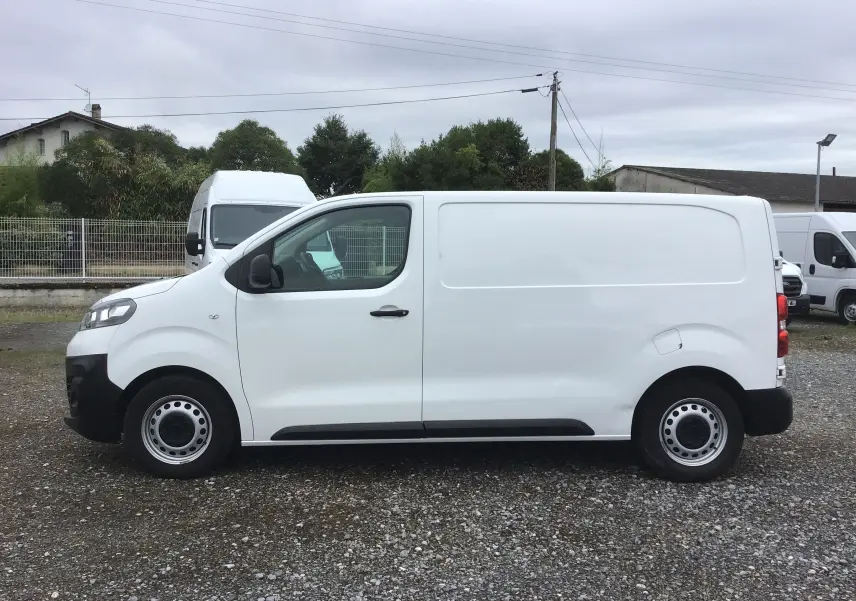 Vue de profil côté gauche d'un utilitaire Opel Vivaro blanc 2022 avec jantes acier et porte latérale coulissante.