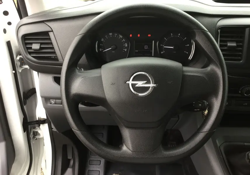 Vue rapprochée du volant noir d'un Opel Vivaro blanc 2022, avec tableau de bord et compteur digital visibles.