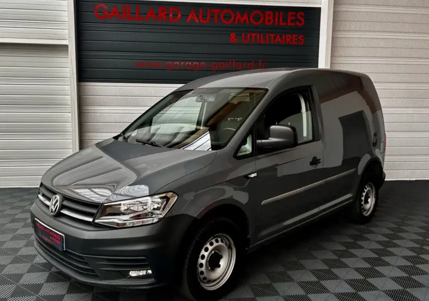 Vue 3/4 avant d'un utilitaire Volkswagen Caddy gris foncé avec calandre noire et jantes acier simples.