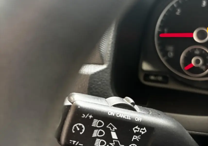 Gros plan sur la commande de régulateur de vitesse et phares dans l'habitacle du Volkswagen Caddy gris foncé 2019.