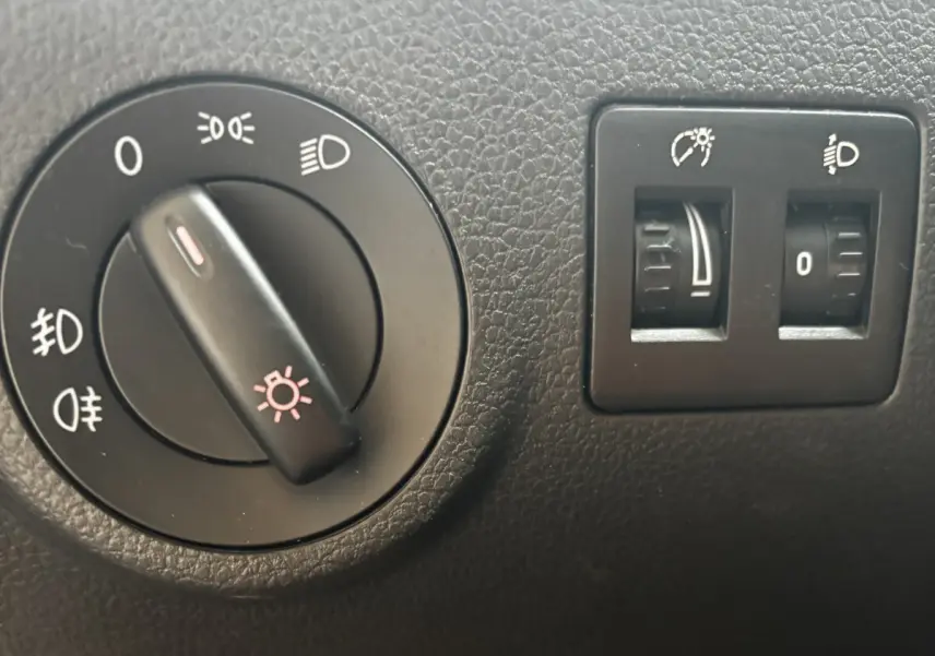 Gros plan sur les commandes d'éclairage et réglage des phares du Volkswagen Caddy gris foncé de 2019.