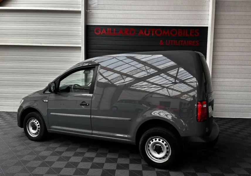 Profil côté gauche d'un utilitaire Volkswagen Caddy gris foncé 2019 avec jantes acier et carrosserie lisse sans vitres arrière.