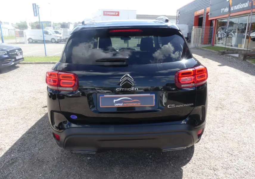 Vue arrière d'un Citroën C5 Aircross noir avec feux arrière LED et logo distinctif sur un parking extérieur.