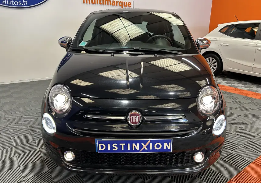 Vue frontale d'une FIAT 500 noire 2023 avec phares allumés et plaque Distinxion en concession multimarque.