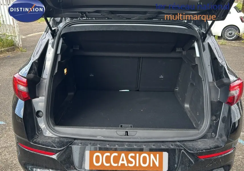 Coffre ouvert en vue arrière d’un Opel Grandland noir 2024 hybride rechargeable, montrant l’espace de chargement vide.
