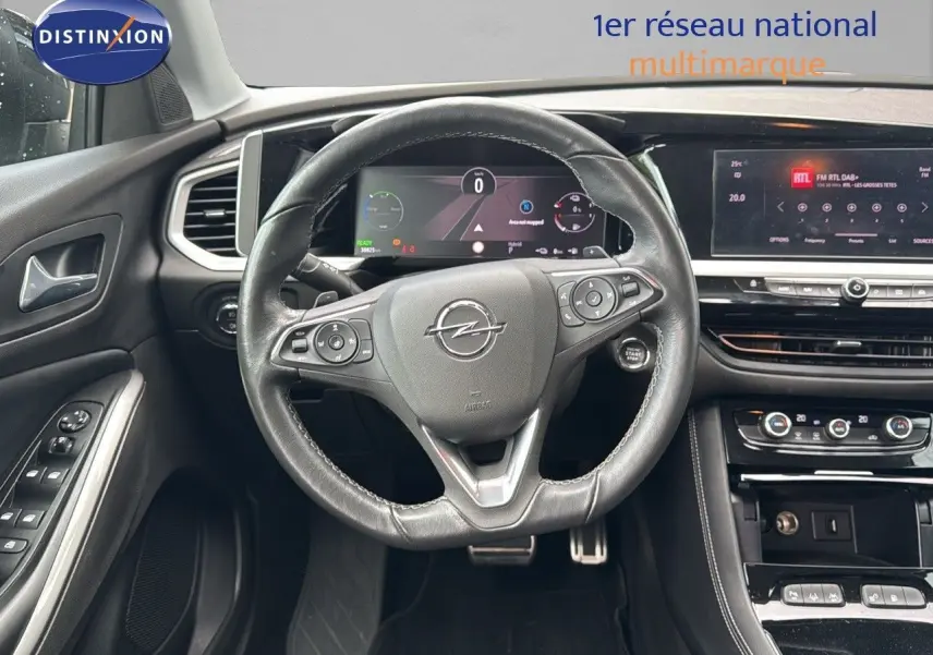 Vue intérieure centrée sur le volant cuir noir d'un Opel Grandland 2024 avec tableau de bord numérique et console moderne.