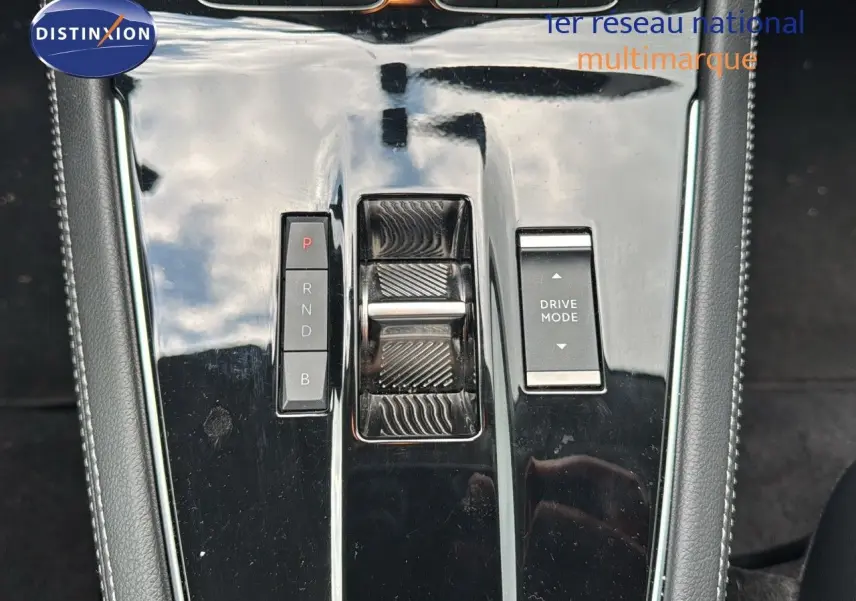 Gros plan sur la console centrale noire brillante de l’Opel Grandland 1.6 Turbo Hybrid 225ch avec commandes de boîte et mode de conduite.