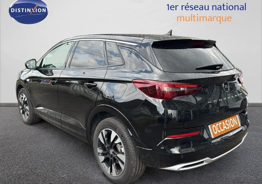 Vue 3/4 arrière droite d'un Opel Grandland noir 2024 hybride rechargeable avec jantes bi-ton et feux LED distinctifs.