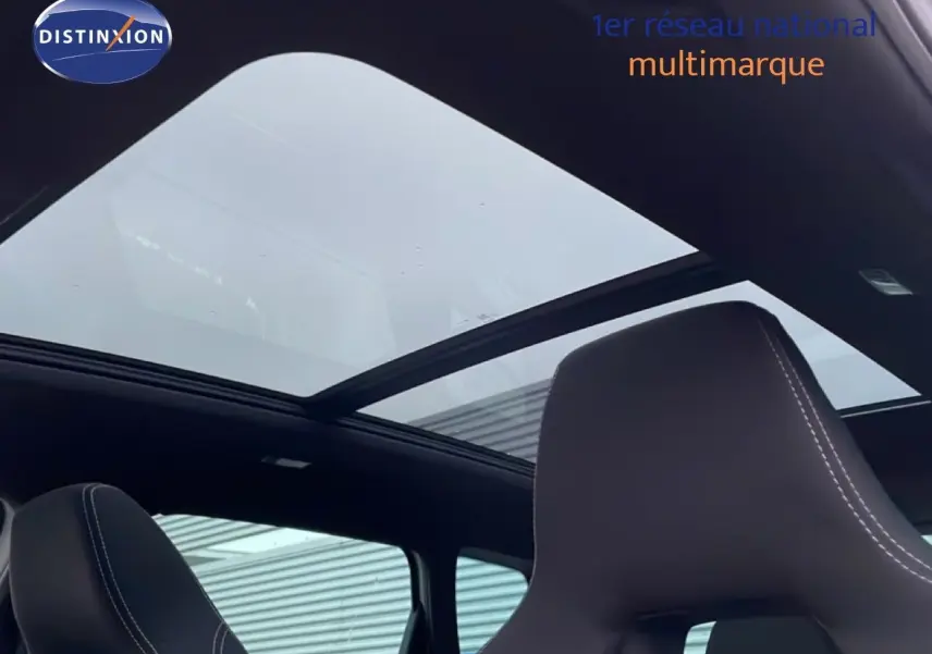 Toit panoramique ouvert vu de l'intérieur sur les sièges noirs avec surpiqûres blanches d'un Skoda Karoq gris argent 2025.