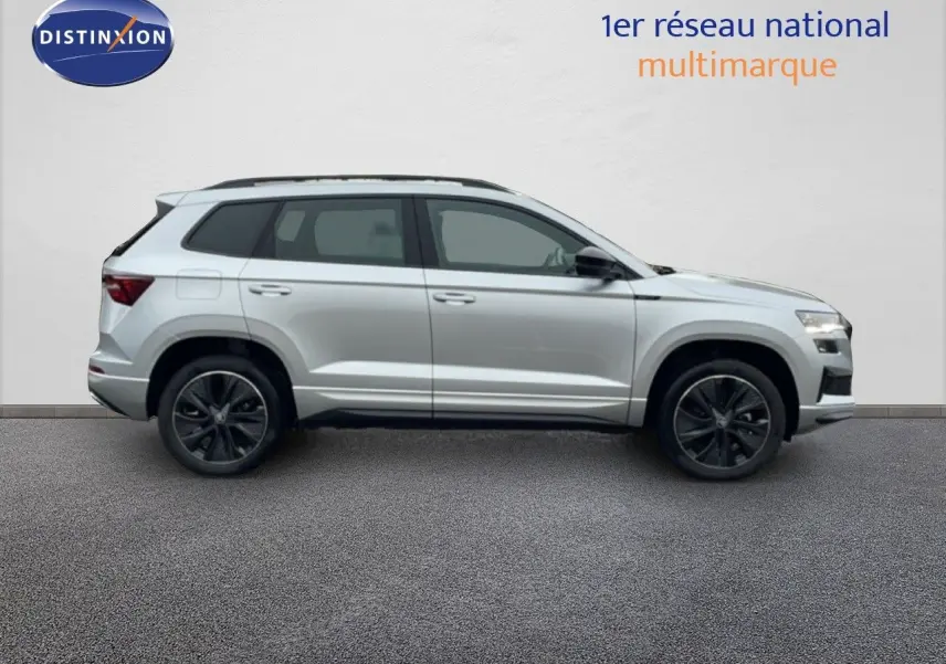 Vue de profil côté gauche d’un Skoda Karoq gris argent métallisé avec jantes noires et toit ouvrant.