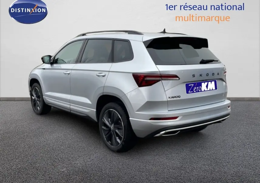 Vue 3/4 arrière droite d’un Skoda Karoq gris argent métallisé 2025 avec jantes noires et vitres teintées.