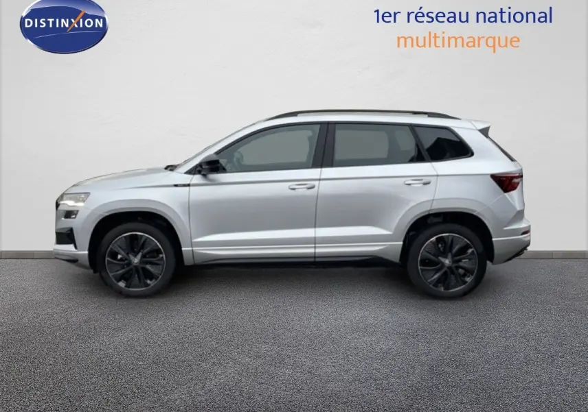 Vue latérale droite d'un Skoda Karoq gris argent métallisé 2025 avec jantes noires et toit ouvrant.