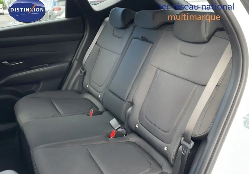 Vue intérieure montrant la banquette arrière en tissu noir du Hyundai Tucson blanc Atlas, porte arrière ouverte côté droit.