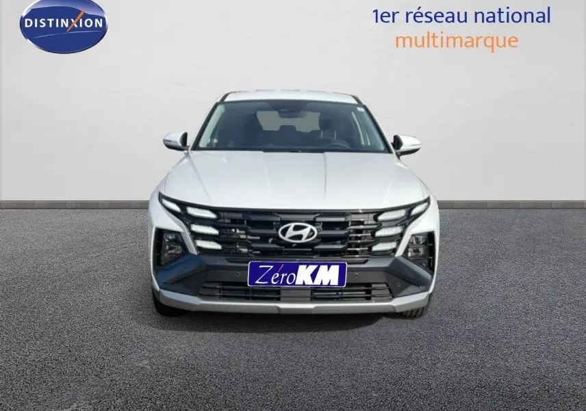 Vue avant du Hyundai Tucson blanc Atlas 2026 avec calandre noire et feux LED distinctifs allumés.