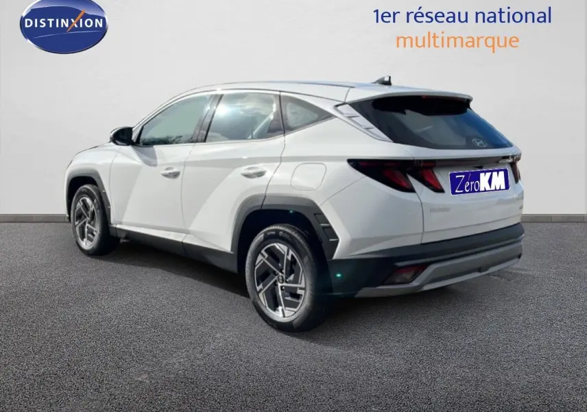 Vue 3/4 arrière droite d’un Hyundai Tucson blanc Atlas 2026 avec jantes bi-ton et feux LED distinctifs.