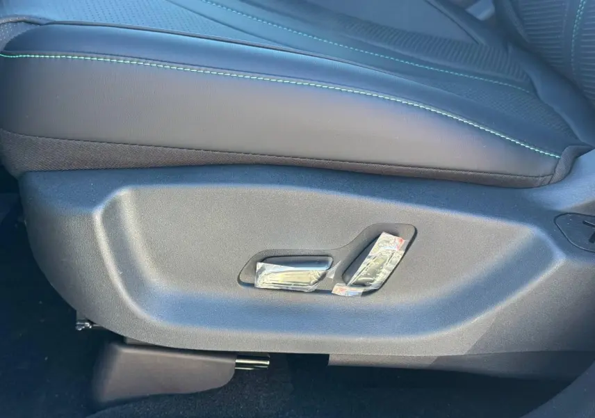 Gros plan sur les commandes de réglage électrique du siège conducteur en cuir noir avec surpiqûres vertes du BYD SEAL U 2026.