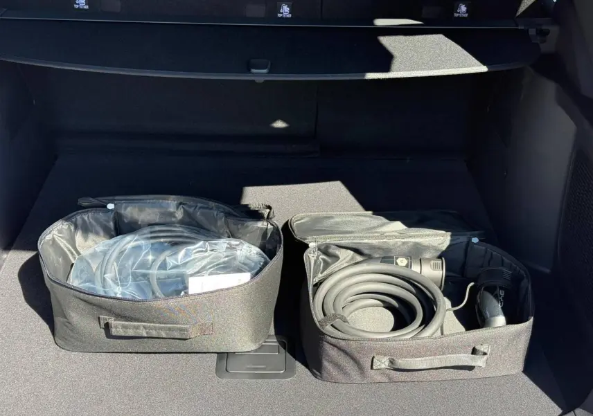 Coffre ouvert du BYD SEAL U 1.5 DM-i 218ch Boost 2026, montrant les câbles de recharge rangés dans des sacs noirs.