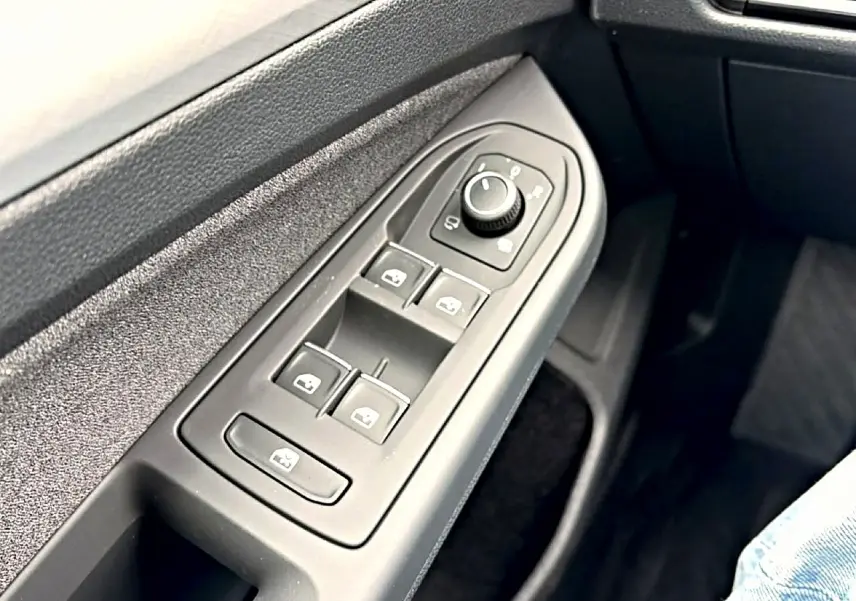 Gros plan sur les commandes des vitres et rétroviseurs côté conducteur de la Volkswagen Golf 1.5 bleu glacier 2026.