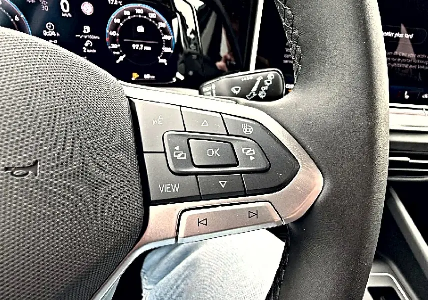 Gros plan sur le volant multifonction noir de la Volkswagen Golf 1.5 etsi evo2 116 life 2026 avec tableau de bord numérique en arrière-plan.