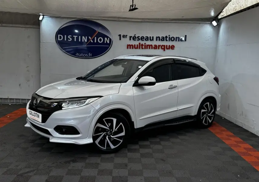 Honda HR-V blanc vue 3/4 avant droit, avec jantes noires et toit noir dans un showroom intérieur.