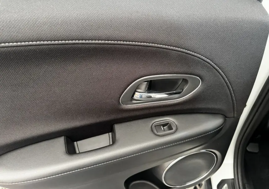Intérieur de la porte arrière droite noire du Honda HR-V blanc, avec poignée chromée et commande de vitre.